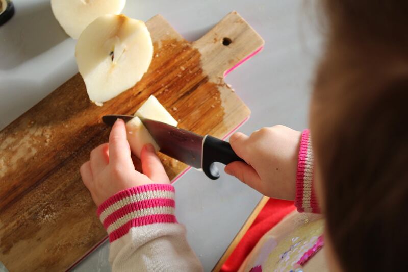 Un enfant coupe une poire sur une planche à découper