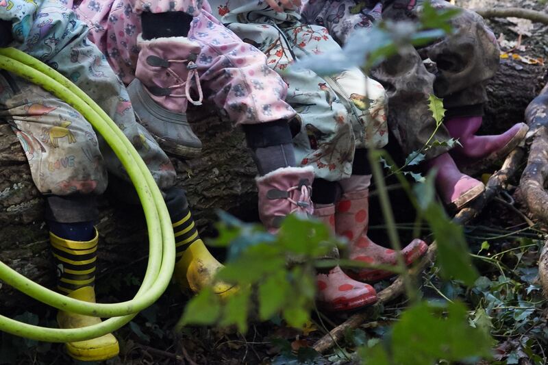 Des enfants en bottes assis sur un tronc