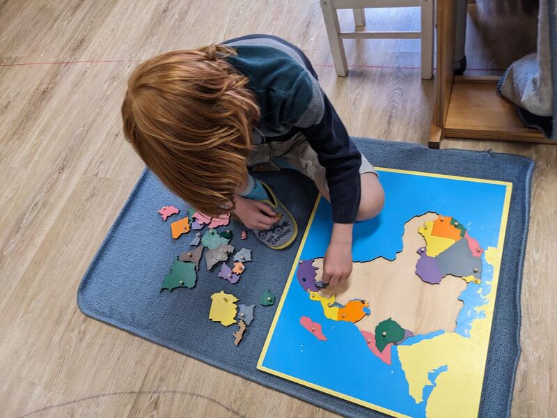 Un enfant assemble une carte puzzle Montessori