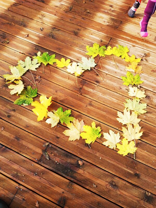 Un cœur de feuilles d'érable posé sur une terrasse en bois
