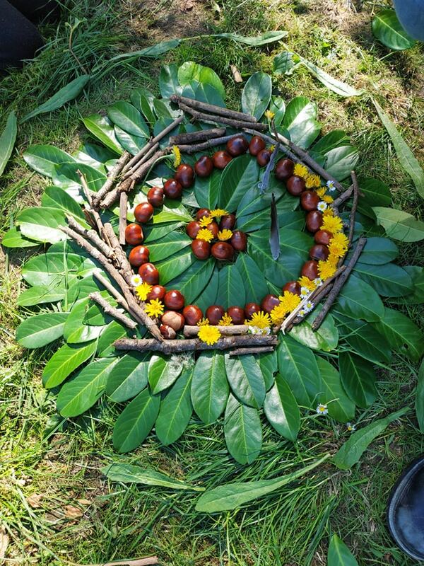 Une création de land art en feuilles, bâtons, marrons et fleurs