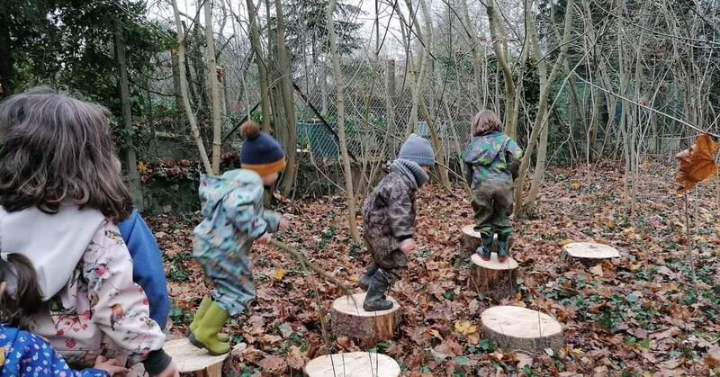 Des enfants sautent de rondin en rondin dans le bois
