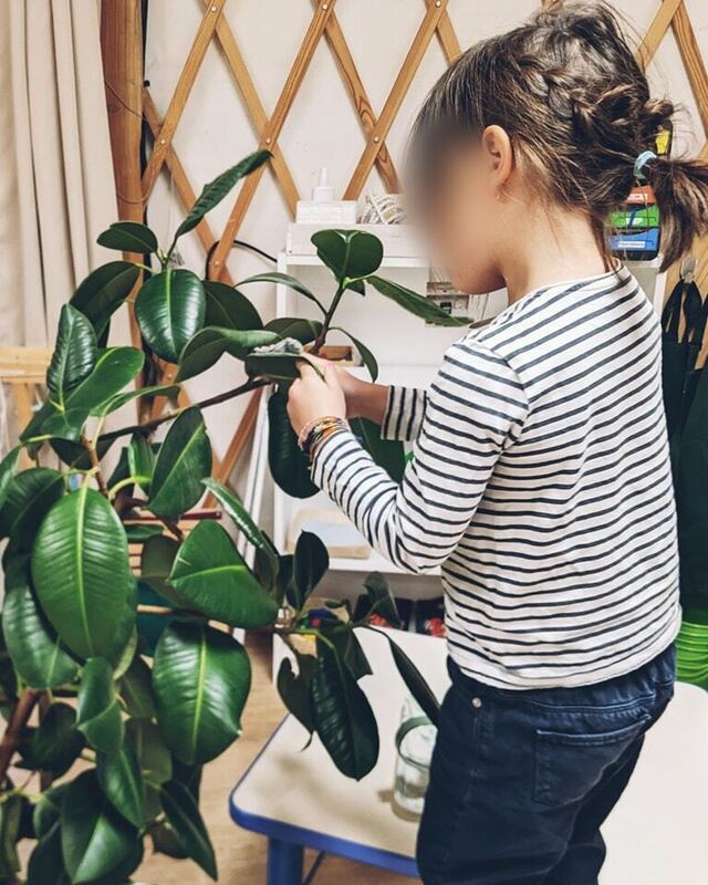 Une élève prend soin d'une plante verte dans la yourte